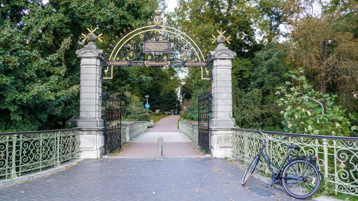 Charming ornate gate at Kronenburgerpark entrance in Nijmegen, Netherlands with a parked bicycle.